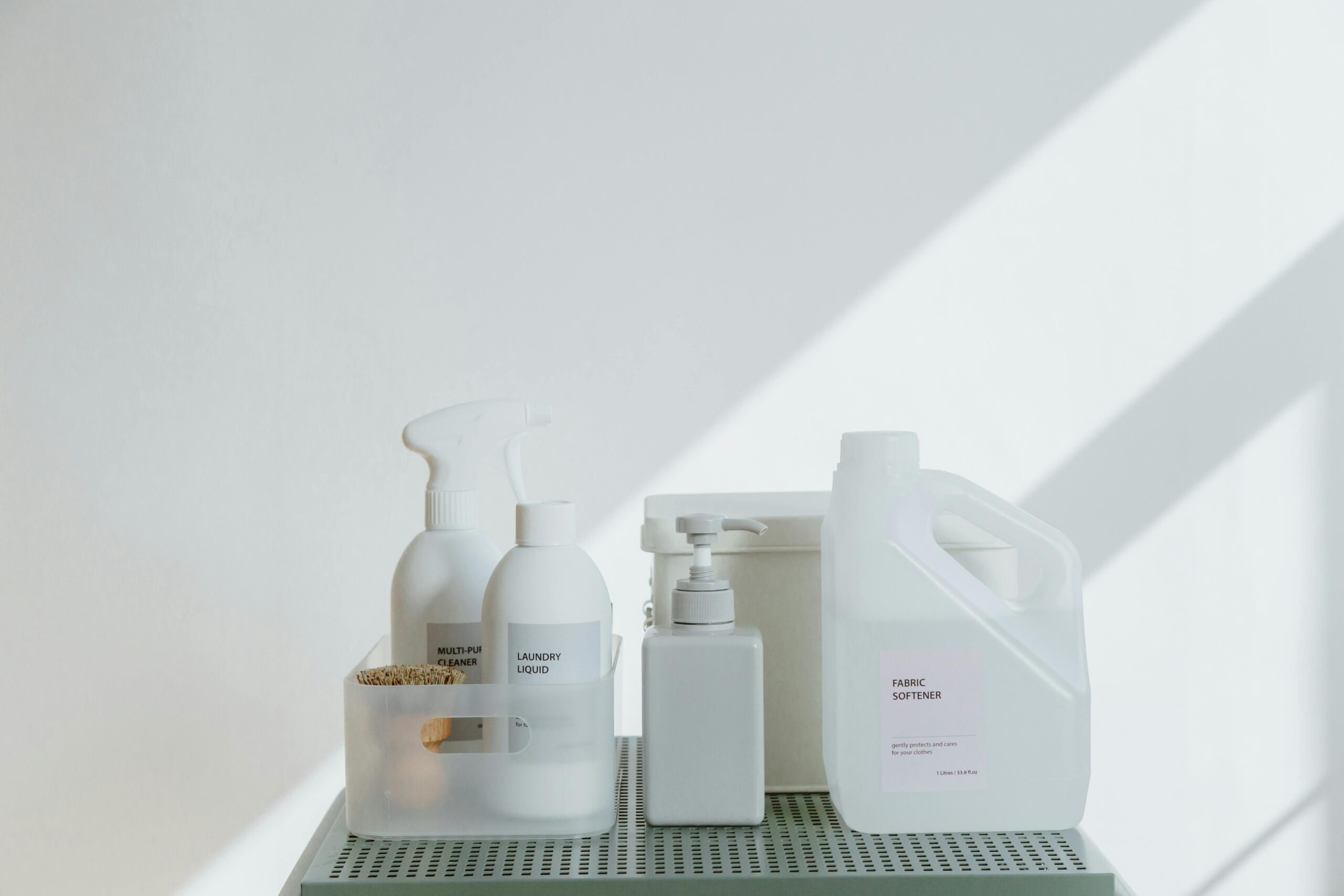 Clean and simple display of various cleaning products in soft lighting on a white background.